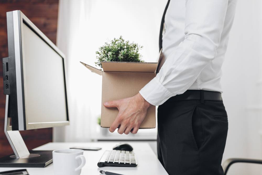  Un desarrollador de software guarda sus pertenencias en una caja de cartón, simbolizando el impacto de la alta rotación de personal en equipos de tecnología.